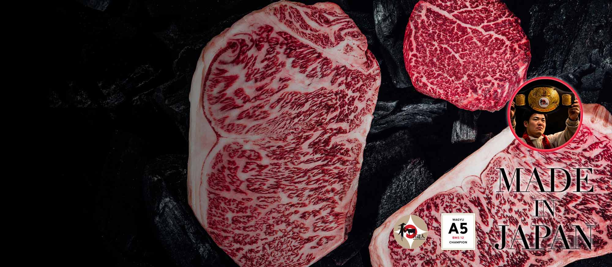 Drei stark marmorierte Wagyu-Rindersteaks der Güteklasse A5 BMS 12 auf dunklem, kohleähnlichem Hintergrund. Unten rechts steht "MADE IN JAPAN". Ein Champion hält einen goldenen Gürtel hoch.